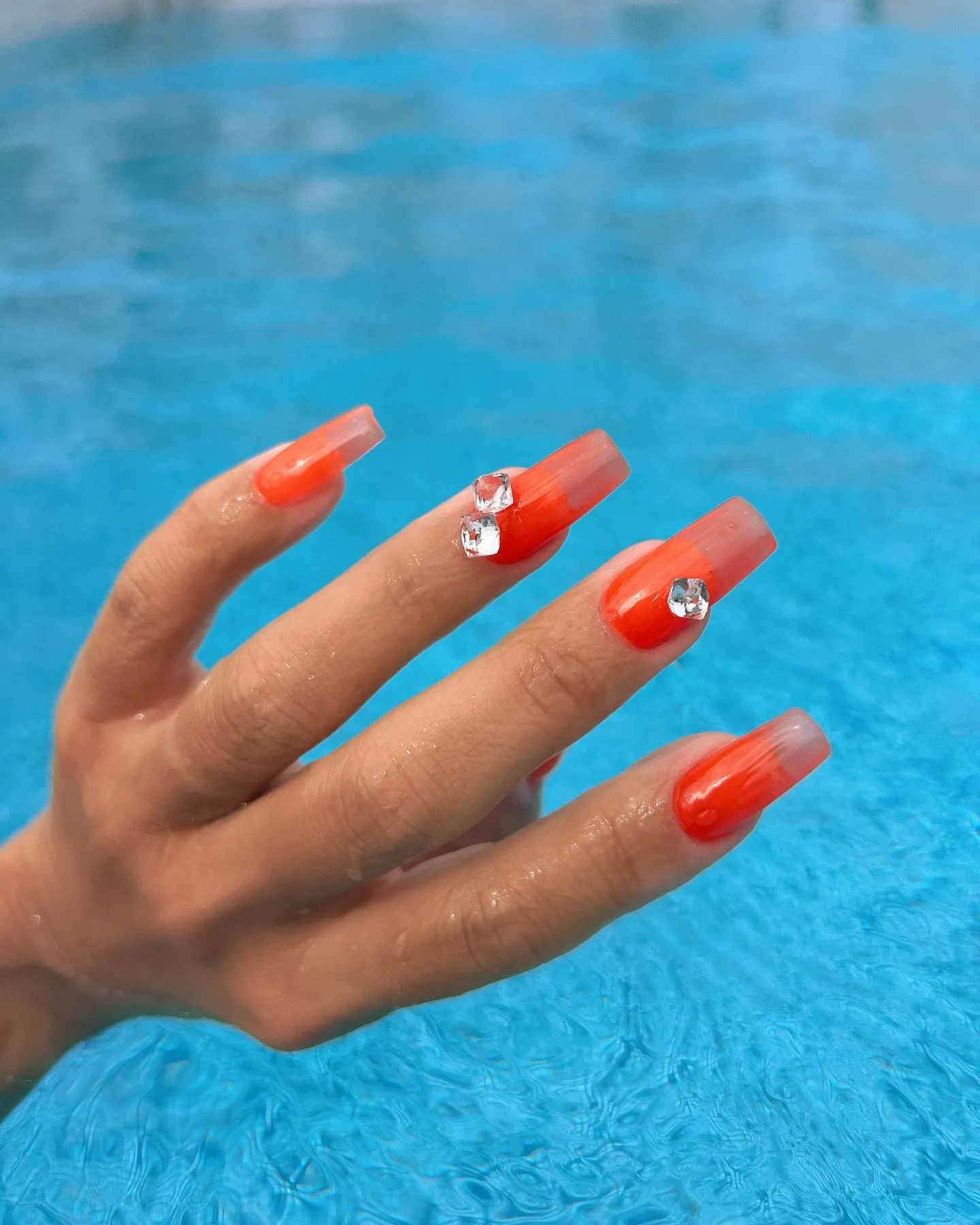 Orange spritz-inspired nails with oversized rhinestones