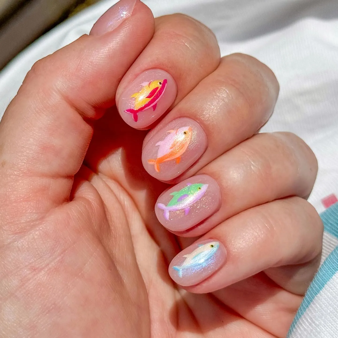 Colorful iridescent fish nail art on a pearly base