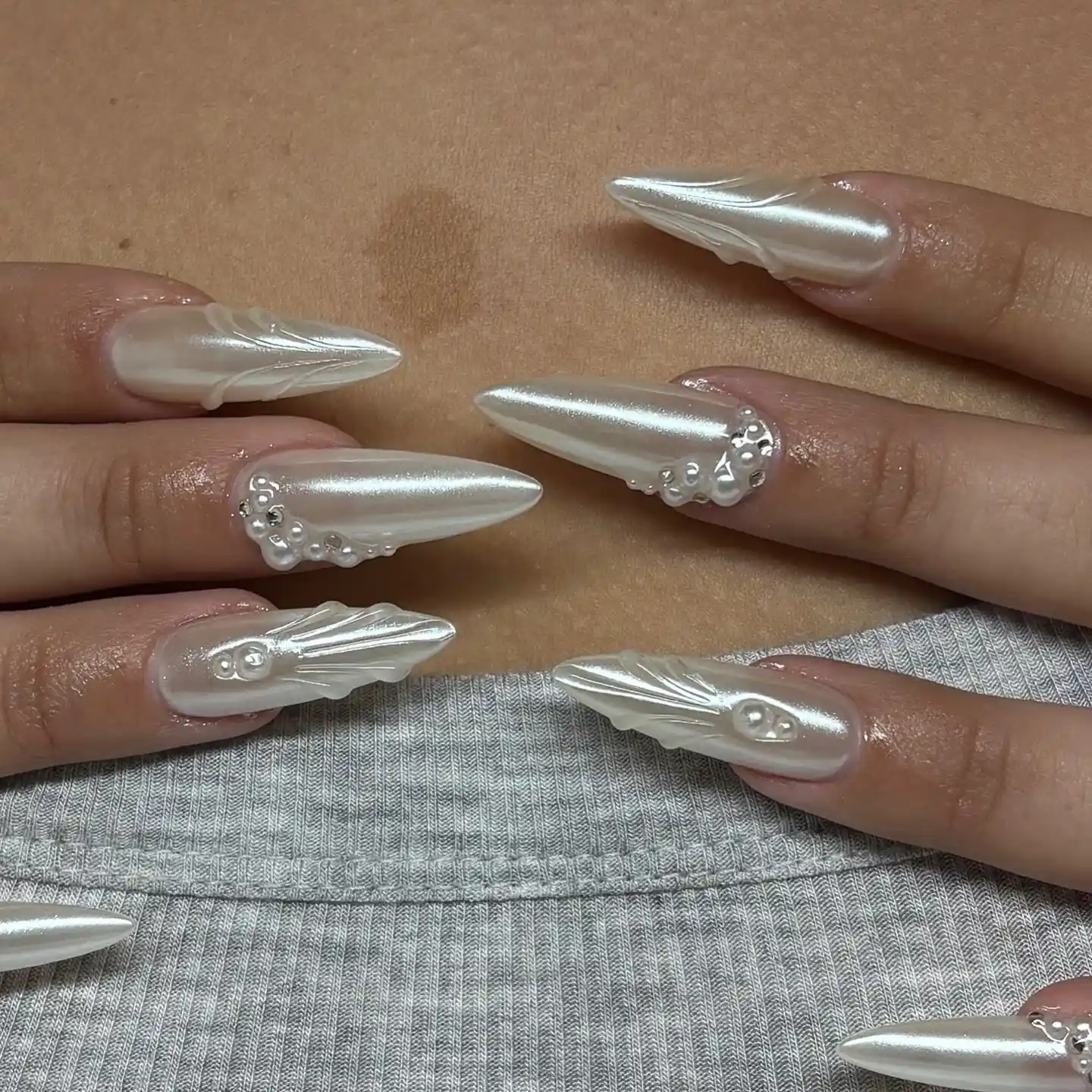 Pearly white chrome almond nails with tonal 3D accents